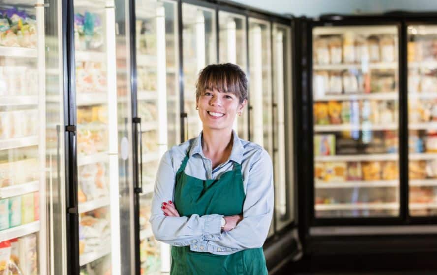 Mujer parada frente a refrigeradores comerciales en supermercado