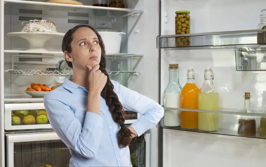 Mujer pensativa mirando su refrigerador