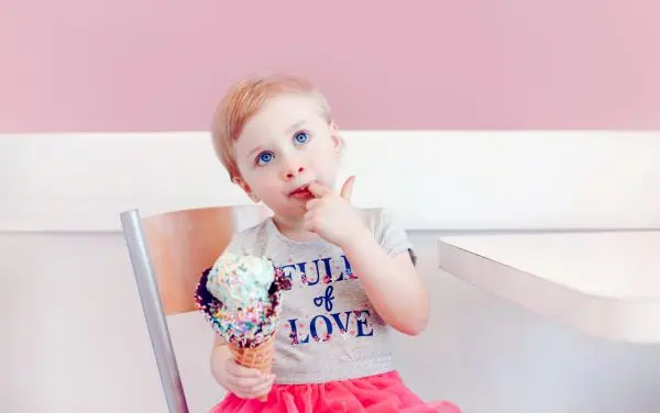 Niña rubia comiéndose un helado en una heladería